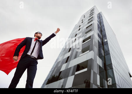 Ein Superheld Geschäftsmann hebt seine Hand gegen eine Busines Stockfoto