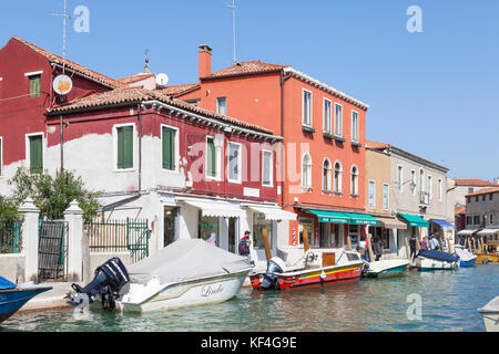 Die bunten Geschäfte und Gebäude auf dem Rio dei Vetrai, Murano, Venedig, Italien mit angelegten Boote im Kanal und Menschen vorbei gehen. Stockfoto