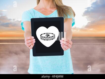 Digital composite von Frau mit Tablet mit Geld in Herz Symbol Stockfoto