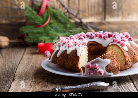 Kandierte Preiselbeeren bundt Cake mit Zitrone Zucker Glasur auf Holzbrett. hausgemachte Herbst und Winter gemütliches Dessert auf rustikalen Tisch Stockfoto
