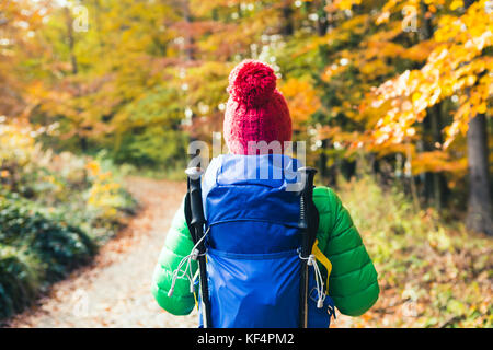 Wandern Frau mit Rucksack auf der Suche nach inspirierenden Herbst goldene Wälder. Fitness Reisen und gesunden Lebensstil im Freien im Herbst Saison. Reisen Fema Stockfoto
