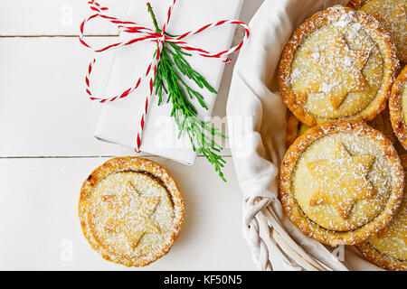 Traditionelle britische Weihnachten Backwaren dessert Hausgemachte mince pies mit Apple Rosinen Nüsse ausfüllen Weidenkorb. golden Mürbteig weiß gepudert. Stockfoto