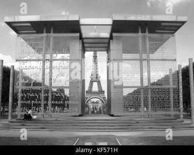 Die Friedensmauer (Mur de la Paix) im Parc du Champ de Mars, Paris, Frankreich, umrahmt den Eiffelturm: Das Wort "Frieden" ist in 49 Sprachen eingeschrieben Stockfoto