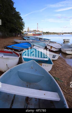 Viele Ruderboote auf dem Strand durch die glänzenden River Deben an einem hellen, sonnigen Oktober Nachmittag. Waldringfield Segelclub, Suffolk. Stockfoto