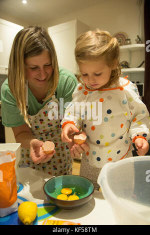 Mutter und Tochter das Mischen von Zutaten in der Vorbereitung für das Backen eines Kuchens Stockfoto