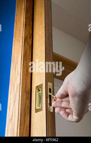 Öffnen Sie Pocket Tür mit männlichen Hand am Hebel ziehen Kante auf dem Griff auf die Tür in der Wand Hohlraum in einem niedrigen Winkel versteckt Stockfoto