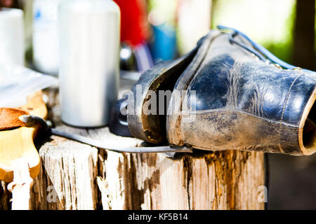 Alte leder Boot mit dem alleinigen lockert sich auf einem alten verwitterten Baumstamm im Freien in der Nähe zu sehen. Stockfoto