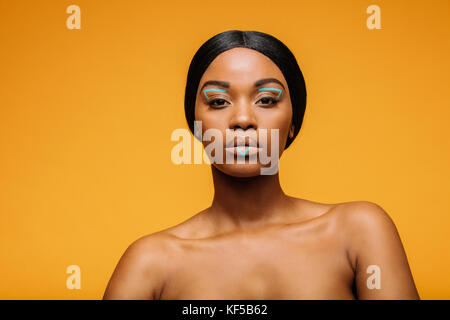 Junge Frau mit künstlerischen lebendige Make-up. Portrait der weiblichen Mode Modell an Kamera auf gelben Hintergrund. Stockfoto