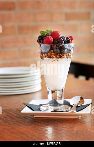 Nahaufnahme einer köstlichen Parfait in einem transparentem Glas mit Schichten von Muttern und Frische verschiedene Beeren serviert. Stockfoto