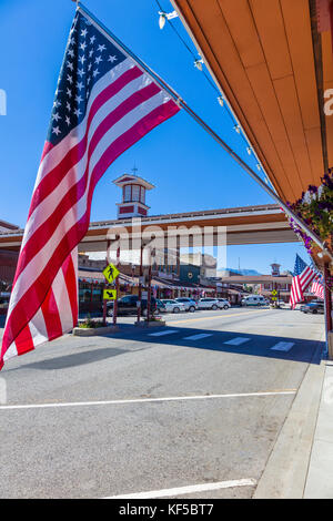 Amerikanische Flagge mit überdachtem Quersteg im Hintergrund auf der Cottage Ave in der Innenstadt von Cashmere, einer Stadt im Chelan County, Washington, USA Stockfoto