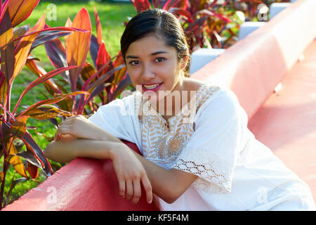 Mexikanische Latin Frau mit ethnischen Kleid im Garten Parkbank sitzen Stockfoto