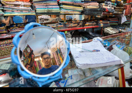 Shiraz, Iran - 19 April, 2017: Ein junger textile Trader ist in dem Spiegel reflektiert. Stockfoto