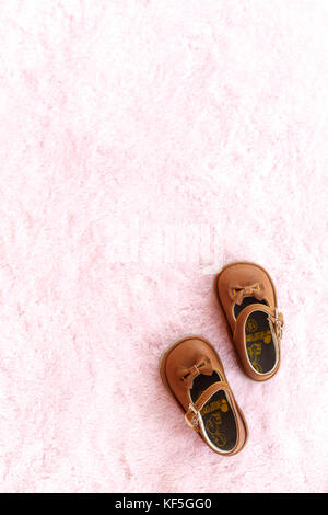 Paar braune mary jane style Baby Schuhe gegen eine blass rosa Hintergrund. Stockfoto