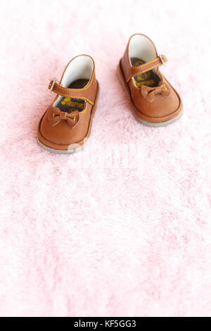 Paar braune mary jane style Baby Schuhe gegen eine blass rosa Hintergrund. Stockfoto