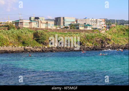 Die Leute fahren Kajak auf der smaragdfarbenen Meeresseite in der Nähe des Handam Strandes auf Jeju Island, Korea Stockfoto