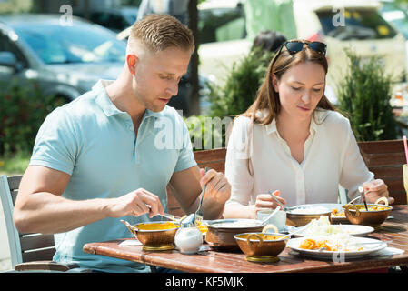 Junges Paar sitzt auf der Bank gemeinsamen Mittagessen Stockfoto