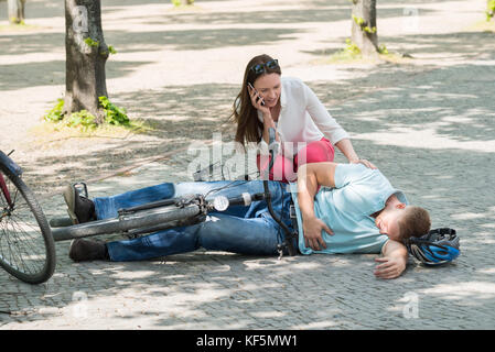 Besorgt Frau um Hilfe ruft nach Mann verletzt herabfallenden vom Fahrrad Stockfoto