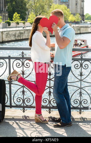 Seitenansicht des Junges Paar Küssen hinter Herzform Stockfoto