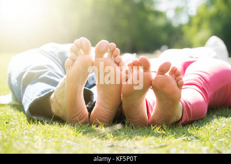 In der Nähe von Paar Füße beim Liegen auf dem Rasen im Park Stockfoto