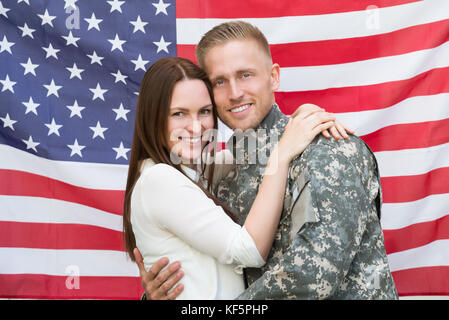 Portrait von jungen männlichen Soldat mit seiner Frau vor der amerikanischen Flagge Stockfoto