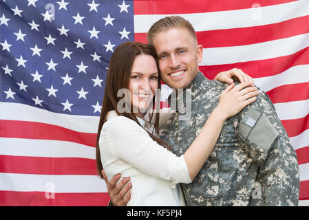 Portrait von jungen männlichen Soldat mit seiner Frau vor der amerikanischen Flagge Stockfoto