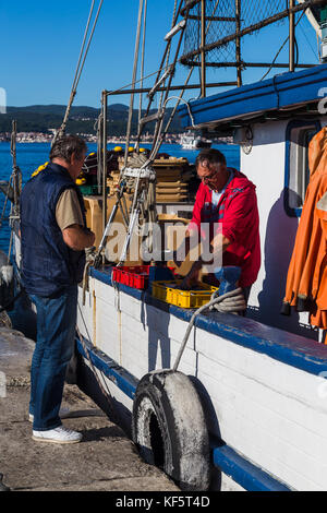 Ein Fischer auf einem Trawler im Hafen von Vrsar (Kroatien) verkauft frische Fische zu einem lokalen Kunden günstig mit nach Hause zu nehmen. Stockfoto