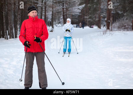 Reifen kaukasischen Vater mit Tochter Skifahren auf Langlaufskiern im Winter Race Track in Wäldern Stockfoto