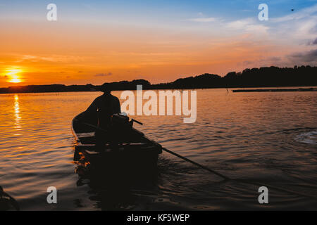 Sonnenuntergang am Abend ein Mann reiten sein long tail Boot in Thailand. Stockfoto