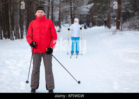 Senior Vater mit Tochter Skifahren auf Langlaufskiern im Winter Wald Stockfoto