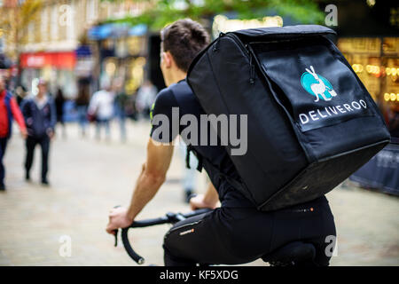 Er ist Deliveroo Treiber und Transport von Lebensmitteln, um kommenden per Handy und sie Reisen mit dem Fahrrad. Stockfoto