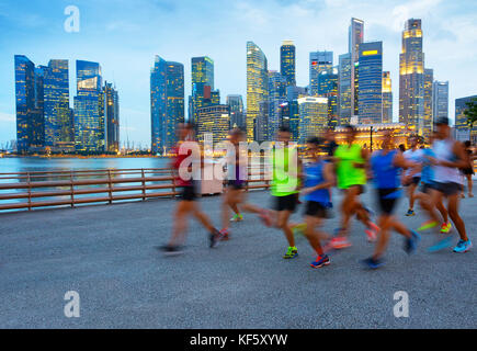 Gruppe von Läufern auf Singapur Kai bei Dämmerung, Singapore Downtown auf einem Hintergrund Stockfoto