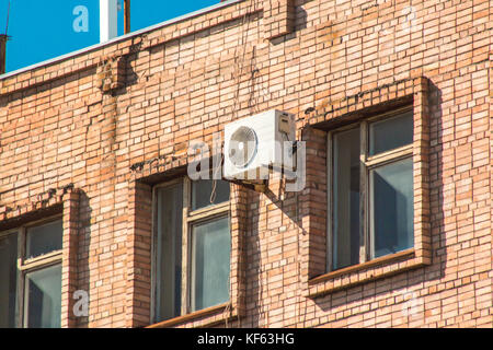 Klimaanlage an der Wand eines Gebäudes zwischen den Fenstern auf der obersten Etage. Stockfoto