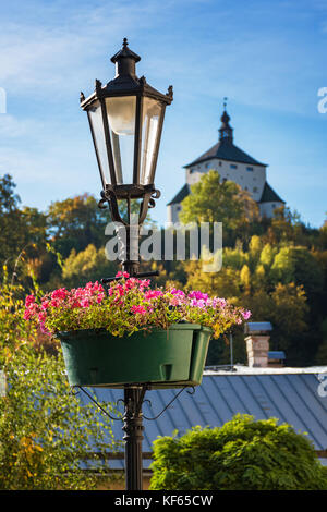 Lampe mit Blumen und das neue Schloss im Hintergrund in Banska Stiavnica, Slowakei, Unesco Stockfoto