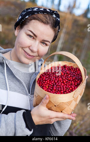 Junge Frau mit Korb voller Reife rote Heidelbeeren Stockfoto
