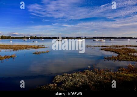 Boote und Spiegelungen im glänzenden Fluss Deben an einem strahlend sonnigen Oktobernachmittag. Waldringfield, Suffolk. Stockfoto