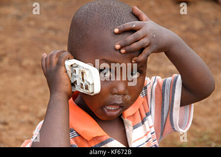 Leben im Slum in Kenia Aerias - Junge kid Spielen mit Handy ist beschädigt Stockfoto