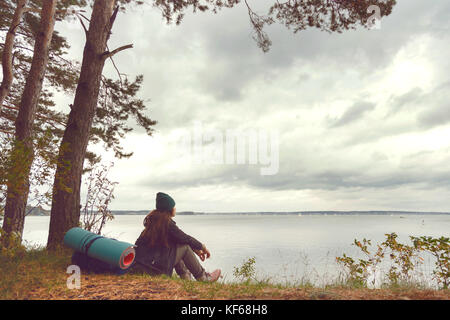 Reisen einsame Frau sitzt in der Nähe von Wald, See und weit weg suchen Stockfoto