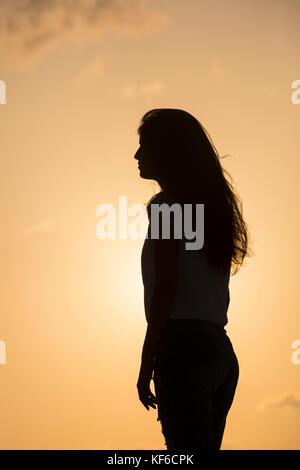 Silhouette einer jungen Frau gegen einen Sonnenuntergang Himmel stehen Stockfoto