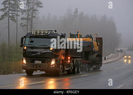 Salo, Finnland - Februar 6, 2016: Volvo fm Lkw schleppt ein Volvo Raupenbagger an einem nebligen Winter Nachmittag im Süden Finnlands. Stockfoto