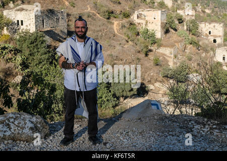 Jerusalem, Israel. 26 Okt, 2017. Ein religiöser Mensch überstreifen Gebetsriemen, tefilin und wickelte in einem talit, einem traditionellen jüdischen Gebetsschal, rezitiert sein Morgengebet mit Blick auf lifta. Die Welt Denkmäler Fonds, in seine Welt 2018 Denkmäler ansehen, hat sich die Aufmerksamkeit auf 25 Kulturerbe und die Kräfte, die sie bedrohen, unter ihnen das Dorf lifta in Jerusalem. Credit: nir Alon/alamy leben Nachrichten Stockfoto