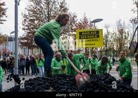 Berlin, Deutschland. Oktober 2017. Greenpeace-Aktivisten werden beobachtet, während sie während einer Demonstration die entladene Kohle auf dem Boden verteilen. Greenpeace-Aktivisten haben vor dem Kanzleramt in Berlin 10 Tonnen Kohle abgeladen. Mit der Aktion wollen sie ihre Nachfrage nach einem schnellen Kohleabgang ausleihen. Die künftige Klima- und Energiepolitik steht im Mittelpunkt der Sondierungsgespräche der Union, der FDP in Berlin in Jamaika. Quelle: Markus Heine/SOPA/ZUMA Wire/Alamy Live News Stockfoto