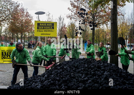 Berlin, Deutschland. Oktober 2017. Greenpeace-Aktivisten werden beobachtet, während sie während einer Demonstration die entladene Kohle auf dem Boden verteilen. Greenpeace-Aktivisten haben vor dem Kanzleramt in Berlin 10 Tonnen Kohle abgeladen. Mit der Aktion wollen sie ihre Nachfrage nach einem schnellen Kohleabgang ausleihen. Die künftige Klima- und Energiepolitik steht im Mittelpunkt der Sondierungsgespräche der Union, der FDP in Berlin in Jamaika. Quelle: Markus Heine/SOPA/ZUMA Wire/Alamy Live News Stockfoto