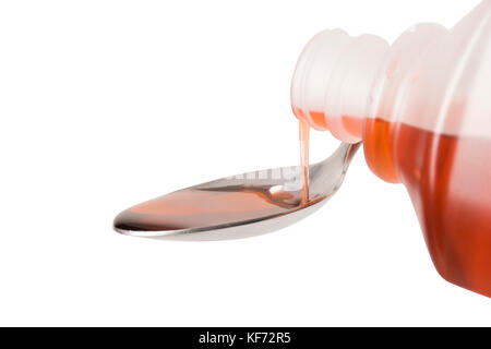 Eine Flasche roten Hustenmedizin auf einem Löffel gegossen wird, konzentriert sich auf das Gießen Stockfoto