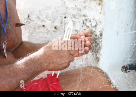 Fischer in roten Hosen flicken Angeln net am Strand der Copacabana in Brasilien Stockfoto