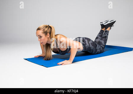 Junge attraktive Frau Üben Yoga, oder drücken Sie die Taste Push-ups ups Übung, Liegestütz, Arbeiten, tragen Sportswear, roten Tank Top, Hose, Hallenbad Stockfoto