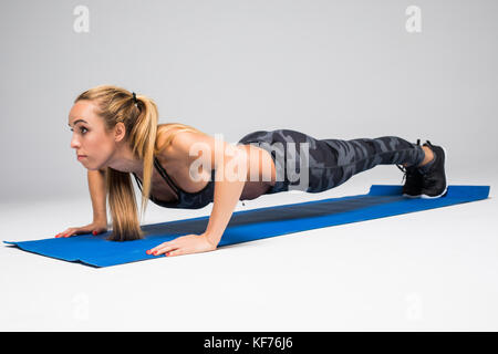 Junge attraktive Frau Üben Yoga, oder drücken Sie die Taste Push-ups ups Übung, Liegestütz, Arbeiten, tragen Sportswear, roten Tank Top, Hose, Hallenbad Stockfoto