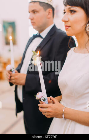 Seite Portrait von Die Happy jungvermählte Paar hält die Kerzen während der wed-Zeremonie. Stockfoto