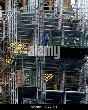 Ein Gerüstbauer blickt von dem Gerüst, das um den Elizabeth Tower, auch bekannt als Big Ben, während der laufenden Restaurierungsarbeiten am Houses of Parliament, Westminster, London, errichtet wird, über London. Stockfoto