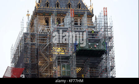 Ein Gerüstbauer blickt von dem Gerüst, das um den Elizabeth Tower, auch bekannt als Big Ben, während der laufenden Restaurierungsarbeiten am Houses of Parliament, Westminster, London, errichtet wird, über London. Stockfoto