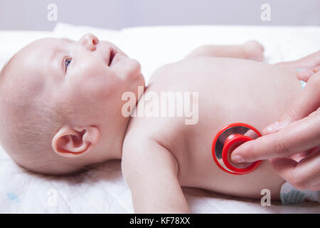 Kinderarzt untersucht neugeborenes Baby Boy mit Stethoskop. Baby lächelt Stockfoto